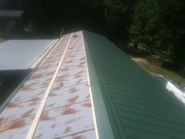Old rusted panels beside newly installed green metal roofing — Wind Damage Roof Repair by Roofing Brothers in Morven