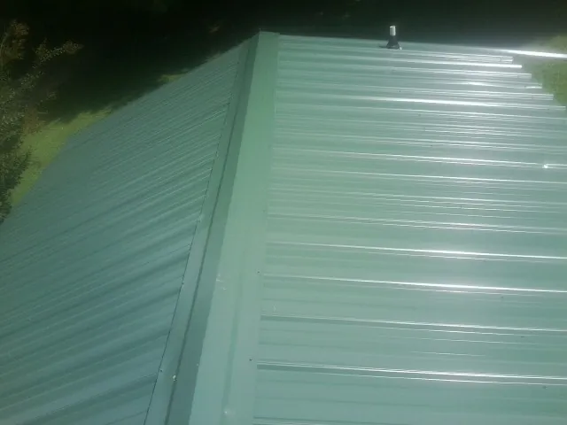 New green metal panels meeting at the ridge of a roof — Flat Roof Repair work by our crew in Morven
